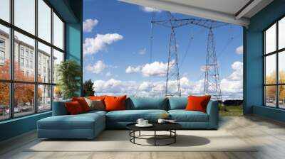 High voltage pylons against the blue sky with white clouds and bright green meadow. Power lines stretching into the distance. Perspective. Electricity Wall mural