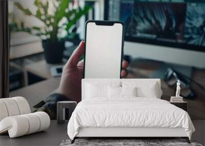 Cropped image of smart man's hands holding and using a white blank screen smartphone while sitting at the working desk over comfortable living room as Wall mural