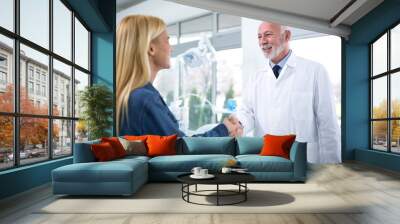 Experienced dentist and satisfied patient are handled Wall mural