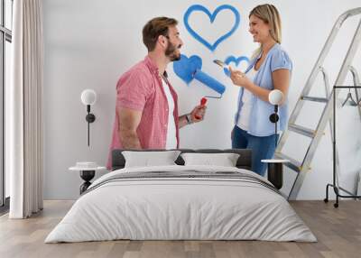 Lovely smiling happy couple painting their new home Wall mural