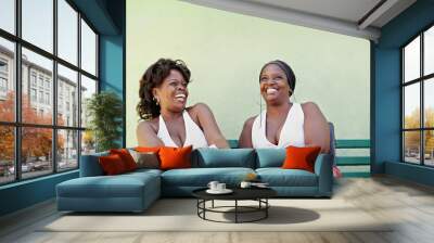 black women with white dress laughing on bench Wall mural