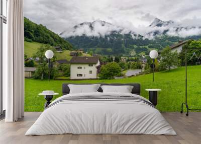 panorama from village Schruns in Montafon, Vorarlberg, with small alpine houses between forested steep slopes and flowered meadows. in the mountains from Rhätikon, at the border to Switzerland, cloudy Wall mural