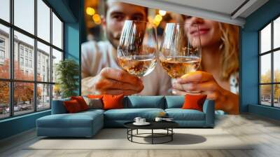 A couple clinking glasses of white wine in a cozy restaurant. The warm lighting and happy expressions create a joyful, intimate atmosphere. Ideal for romance, date night, and celebration themes. Wall mural