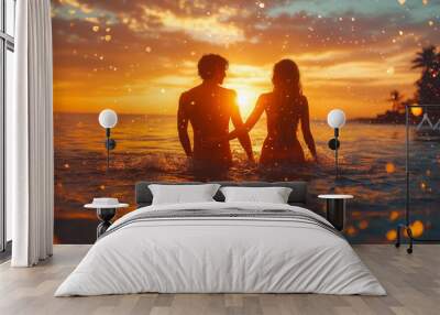 Sunset on the Beach with a Couple. Romantic sunset on the beach with a couple holding hands in the water. Orange and blue hues in the evening sky. Wall mural