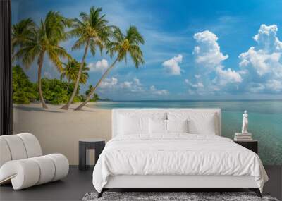 Tropical sea beach scene with clear turquoise water, white sandy shore and palm trees under a bright blue sky on a sunny day Wall mural