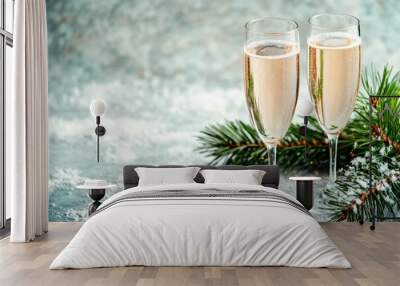 Two champagne glasses filled with bubbly, set against a snowy background with a festive pine branch. Ideal for New Year and holiday celebrations. Wall mural