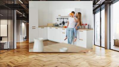 Young couple cooking - man and woman in their kitchen Wall mural