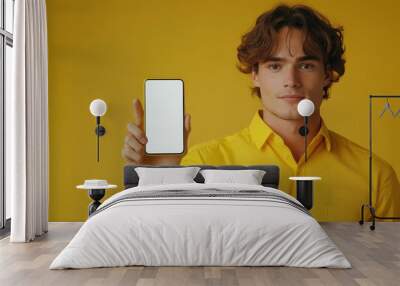 A man in a yellow shirt standing near a huge smartphone with a blank screen and pointing his thumb at it, mockup, copy space, advertising concept, Generative AI Wall mural