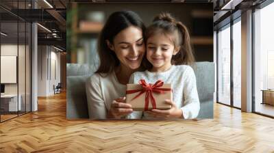 Loving happy mother congratulating her little daughter, presenting gift box, sitting on cozy couch, kid celebrating birthday at home, Generative AI Wall mural