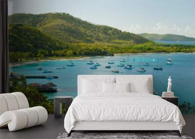 Anchoring ships in tropical bay. Plenty of small yachts on blue sea water, green hills and blue sky in the background. Aerial view of Britannia Bay, Mustique island. Caribbean lifestyle themes Wall mural