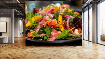 a close-up of a colorful salad on a black plate. The salad contains various ingredients such as leafy greens, slices of red onion, chunks of white cheese, tomato halves, yellow bell pepper strips Wall mural