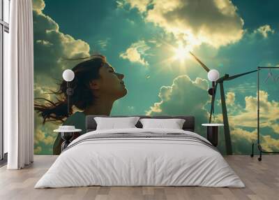 a girl looking up at a wind turbine in the sky with clouds in the background and a sun shining through the clouds Wall mural