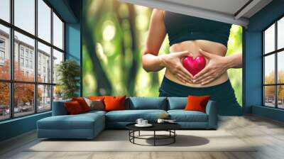 Woman hand's with heart over stomach concept for exercise, diet, fitness, gut health and self love for wellness and training in the summer for healthy workout outside. Wall mural