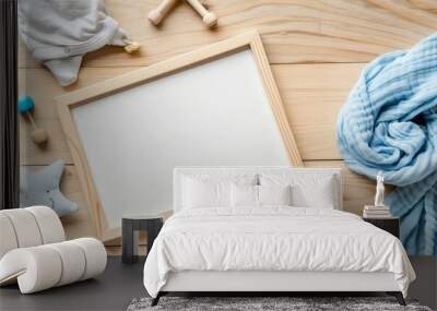 A blank frame surrounded by baby boy themed items on a wooden ba Wall mural