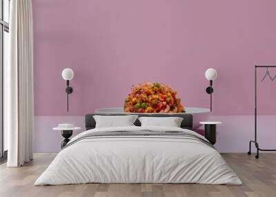 A mound of red and green food on a white plate against a pink background Wall mural