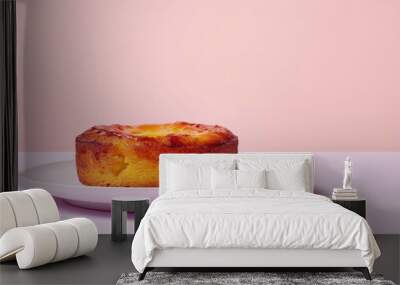 A Single Round Cake on a White Plate Against a Pink Background Wall mural