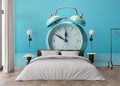 Traditional circular alarm clock with bells and clock hands set against a light blue background Wall mural