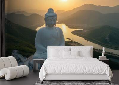 A giant, serene Buddha statue sits peacefully atop a hill, overlooking a serene river winding through mountains as the sun rises, creating a tranquil atmosphere. Wall mural