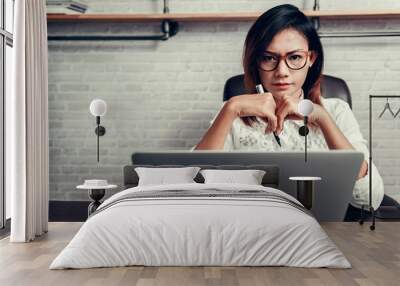 Asian woman with glasses and his pen ready to work. Focus on fac Wall mural