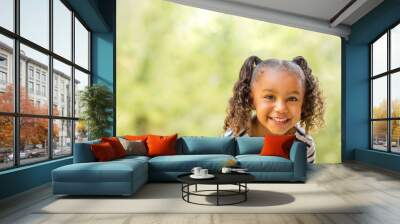 Cute mixed race little girl laughing and smiling. Wall mural