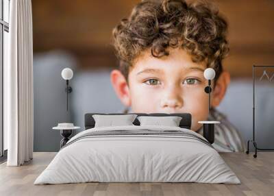 Handsome young boy with curly hair smiling. Wall mural