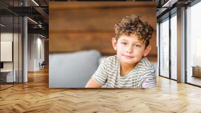 Handsome young boy with curly hair smiling. Wall mural