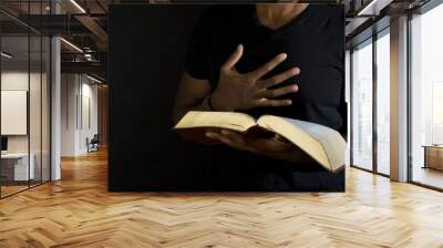 Man reading a bible isolated on black. Wall mural