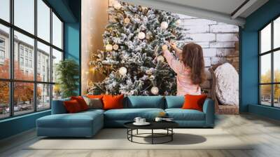 Amazing little girl is decorating the Christmas tree golding a s Wall mural