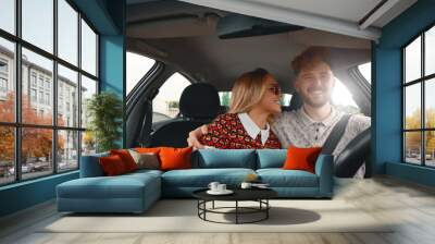 Young couple sitting on the front passenger seats and smiling wh Wall mural