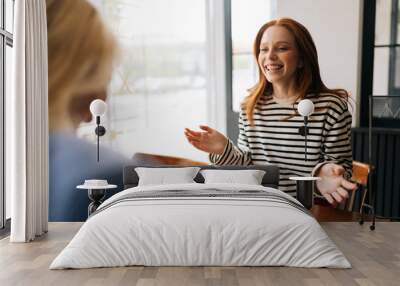 Back view of two happy pretty Caucasian female friends talking laughing at cafe table drinking coffee having fun together enjoy friendship, pleasant conversation. Concept of woman friendship. Wall mural