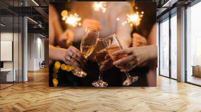 Close-up of glasses of clinking Champagne with Bengali lights. Celebration concept Wall mural