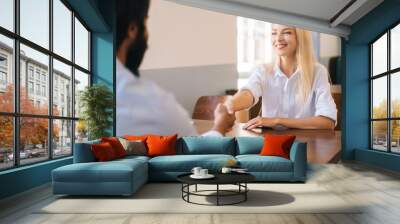 Close-up view from back of unrecognizable bearded business man handshaking with cheerful attractive young woman closing deal at business meeting, job interview, agreement business, selective focus. Wall mural