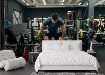 Front view of experienced fitness instructor helping beginner sportsman doing barbell bench press exercise during personal workout in gym. Male doing barbell bench press under couch supervision Wall mural