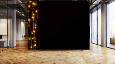 Christmas lights garland border over black background. Flat lay, copy space. Wall mural