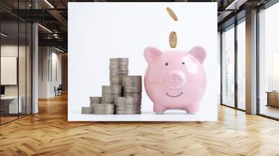 Coins dropping to pink piggy saving bank with coins stacking on white background for save money of deposit to get dividend and profit investment concept. Wall mural