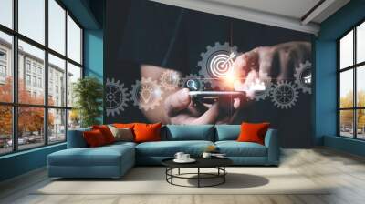 Man touching mobile phone with virtual mechanical gear and target icon , Business achievement target concept. Wall mural