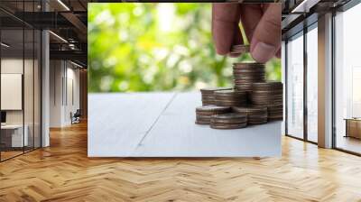 Saving money and investment concept by male hand putting money coins stacking for business growth.-Image. Wall mural