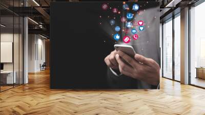 Social media and marketing concept, Businessman holding white smartphone and using colourful social media icons. Wall mural