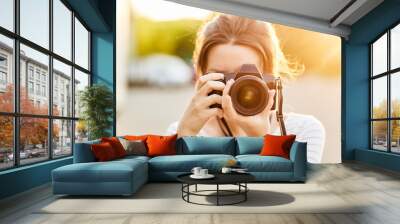 young girl taking pictures on camera in a summer Park at sunset Wall mural