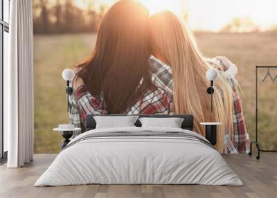 Two young woman looking on the sunset and hugging. Best friends Wall mural