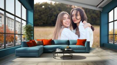 Two young women in white shirts hugging outdoors Wall mural