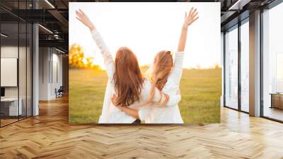 Young women are having fun on the green field in the evening. Wall mural