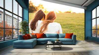 Young women in white sweaters are walking on the green field. Best friends Wall mural