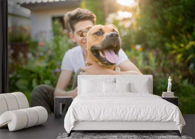 Happy young businessman, affectionately affectionate dog outdoors in sunset. walking with a dog in the park. stafford  Wall mural