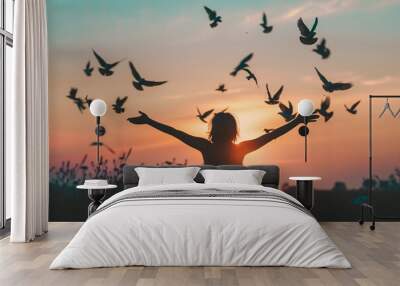 Silhouette of young woman with open arms and flying birds on sunset background. Generative AI Wall mural