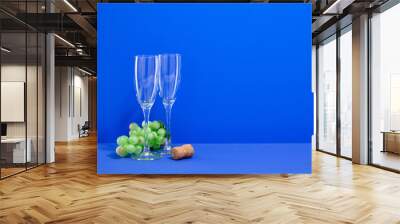 Two wine or champagne glasses on the table. Ripe green juicy grapes and a cork from a bottle of wine. Copy space for text. Wall mural