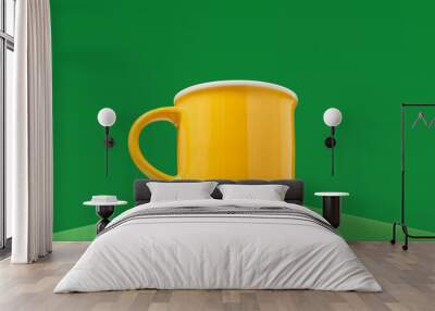 Yellow brightly colored beverage cup on a green background. Wall mural