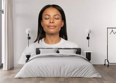 Calm peaceful african american woman with closed eyes and relaxed smile breathing deeply focused on positine thinking and meditating. Young female relaxing or recovering after stress or panic attack Wall mural