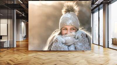 Close portrait of young caucasian woman with long hair in beige hat with fur pompon, scarf, coat, white gloves covered with snow at sunny winter day, / Female wrap in and holding scarf, copy space Wall mural