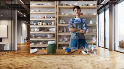 Creative ceramics studio owner at workplace standing arms crossed and looking at camera. Confident entrepreneur crafts woman in pottery studio preparing for master class or work process Wall mural